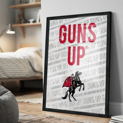 A framed poster with the text "GUNS UP" prominently displayed, featuring a graphic of a person riding a horse with a gun.
