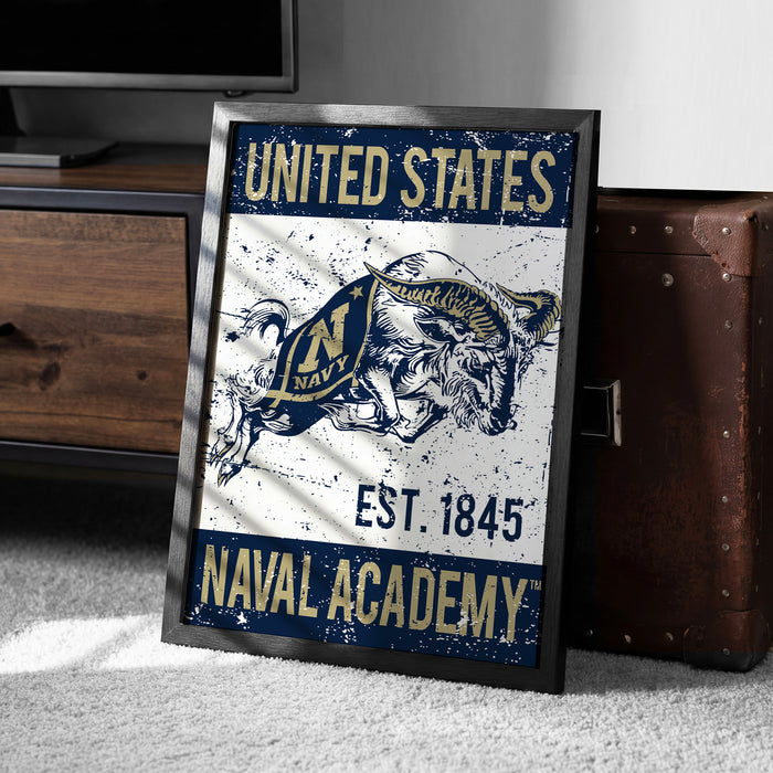 A framed poster with the text "UNITED STATES NAVAL ACADEMY EST. 1845" and an illustration of a bull, which appears to be a design related to the naval academy.