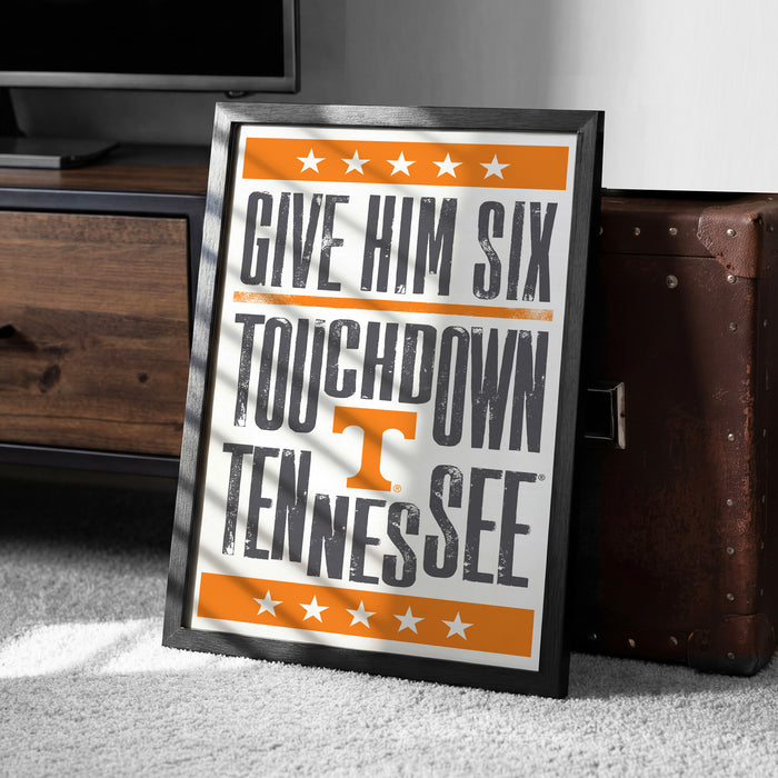 A framed poster with the text "GIVE HIM SIX TOUCHDOWN TENNESSEE" is leaning against a wooden cabinet.