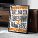 A framed poster with the text "GIVE HIM SIX TOUCHDOWN TENNESSEE" is leaning against a wooden cabinet.
