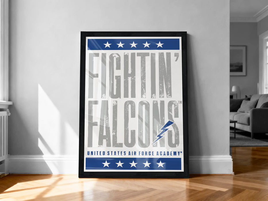 a framed poster with the text "FIGHTIN' FALCONS" and "UNITED STATES AIR FORCE ACADEMY" on it, standing on a wooden floor against a white wall.