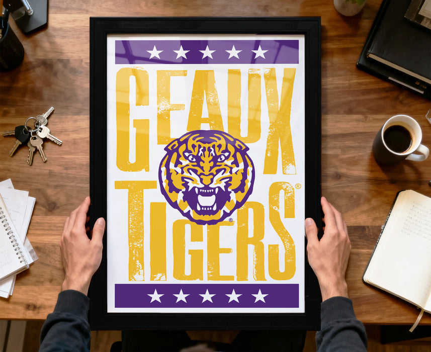 A framed poster with the text "GEAUX TIGERS" and a graphic of a tiger is being held by a person's hands.