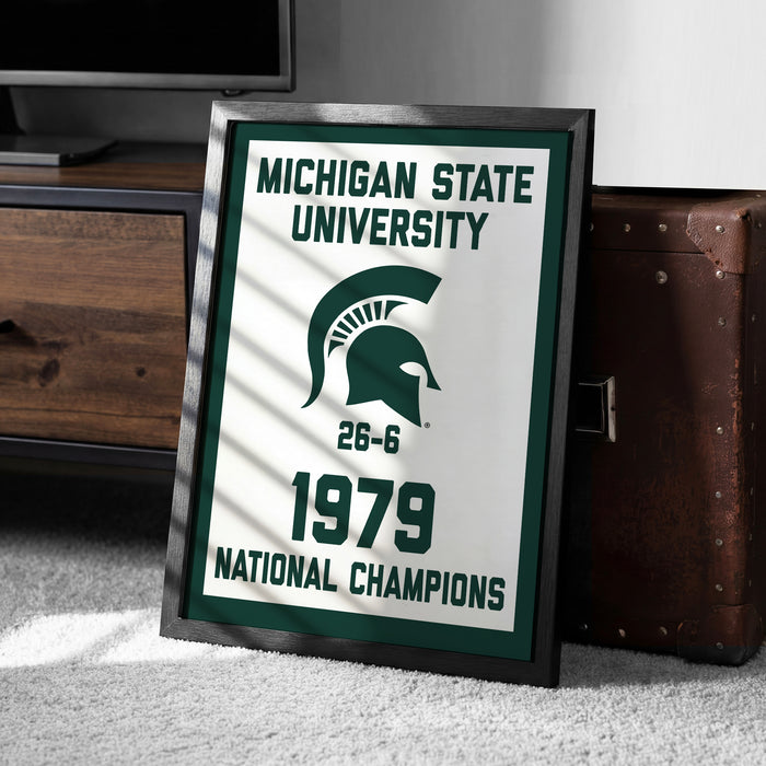 A framed sign displaying the Michigan State University logo and text, indicating that the university was a national championship winner in 1979.