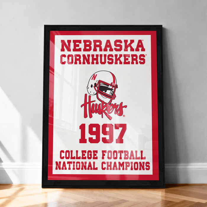 A framed poster celebrating the 1997 Nebraska Cornhuskers College Football National Champions, featuring the team's logo and the text "Nebraska Cornhuskers 1997 College Football National Champions".