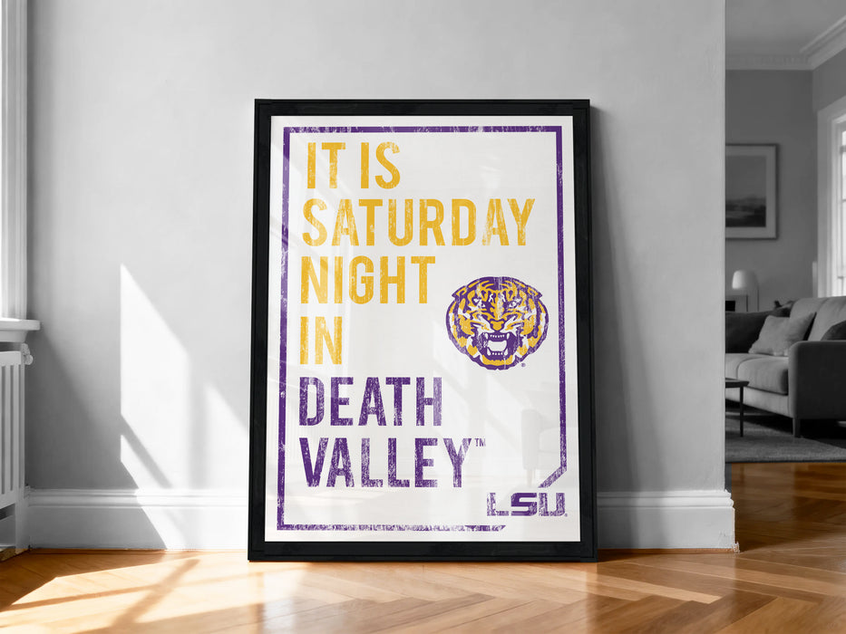 A framed poster with text and a tiger logo, placed on a wooden floor against a white wall.