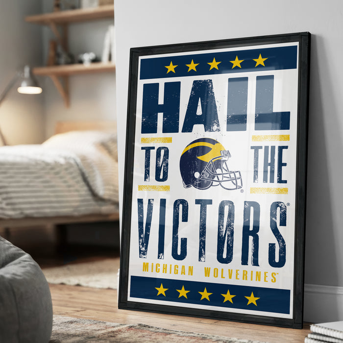 A framed poster with the text "Hail to the Victors" and a football helmet graphic, promoting Michigan Wolverines.