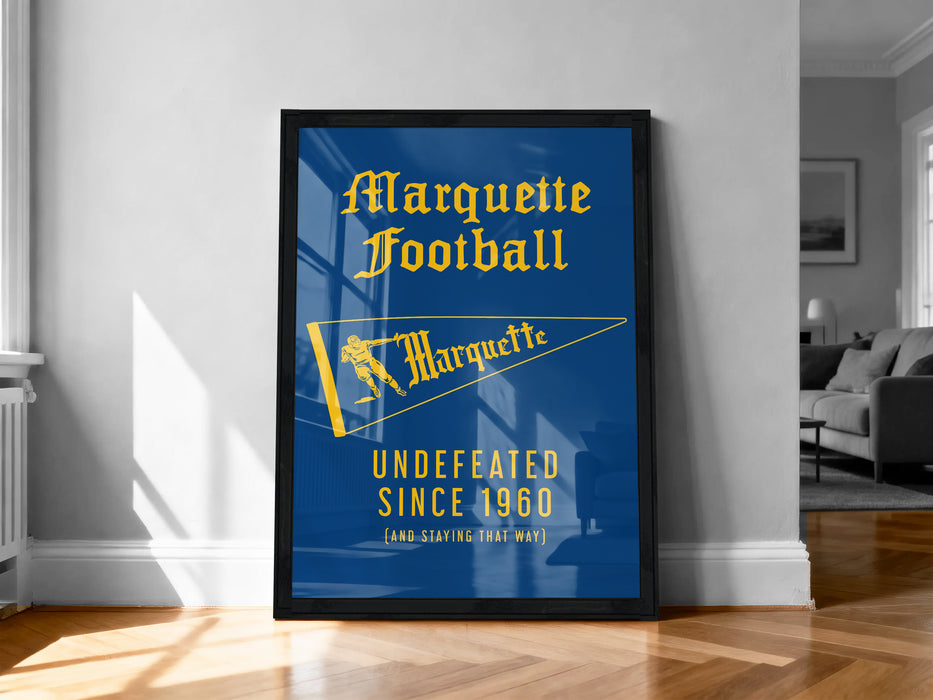 A framed poster on a wall, featuring the text "Marquette Football" and "UNDEFEATED SINCE 1960" along with a yellow flag design.