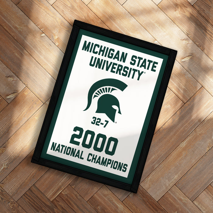 A framed poster with the text "Michigan State University" and "32-7 2000 NATIONAL CHAMPIONS" on it, along with a logo of a helmet.