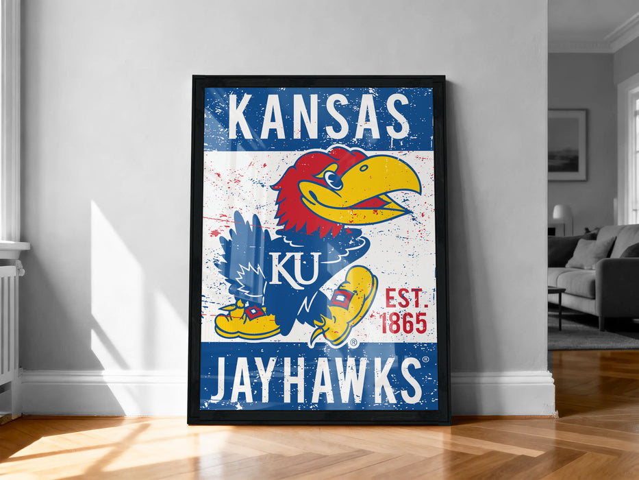 A framed poster of the Kansas University Jay Hawks, a sports team, is displayed on a wall in a room.