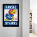 A framed poster of a Kansas University Jayhawks, a sports team, is hanging on a wall.