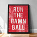 a framed poster with the text "RUN THE DAMN BALL" in bold, white letters against a red background.