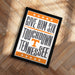 A framed poster with the text "GIVE HIM SIX TOUCHDOWN TENNESSEE" printed on it, placed on a wooden floor.