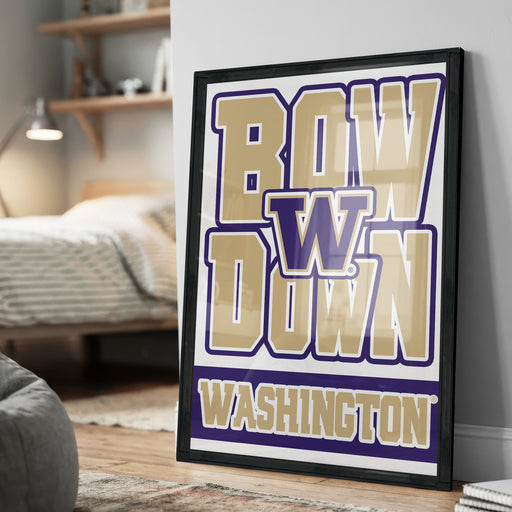 A framed poster with the text "BOW W DOWN WASHINGTON" displayed prominently on it, placed on a wall in a room.