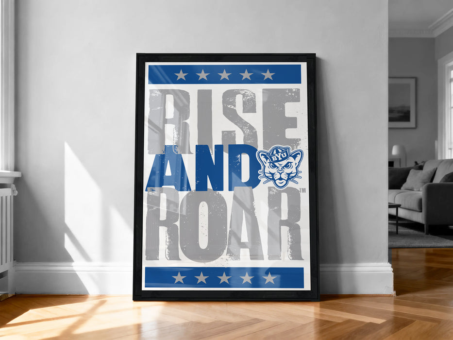 a framed poster with the text "RISE AND ROAR" and a cat logo, displayed on a wall in a room.